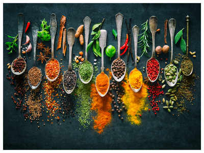 Spoons with different types and colors of herbs and spices on black background