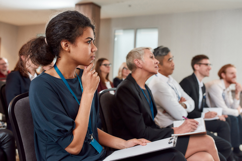 Forward-thinking. Multi-ethnic audience sitting in a row while listening to presentation at conference hall