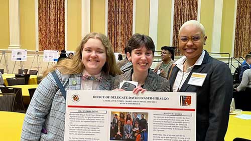 Students smiling in front of a poster presenting their work