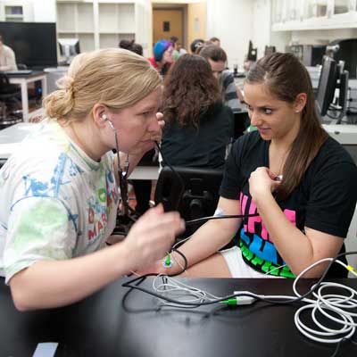 Woman holding stethoscope to another woman's heart