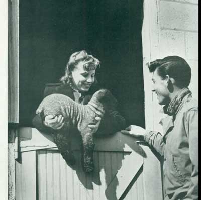 Historical picture of woman holding lamb out of farm