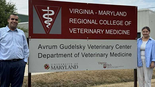 Kazakhstan interns smiling in front of Virginia-Maryland College of Veterinary Medicine sign. 