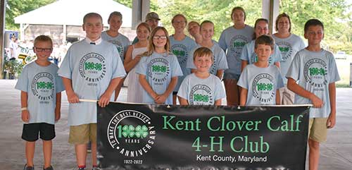 Group of kids smiling holding up a 4-H banners