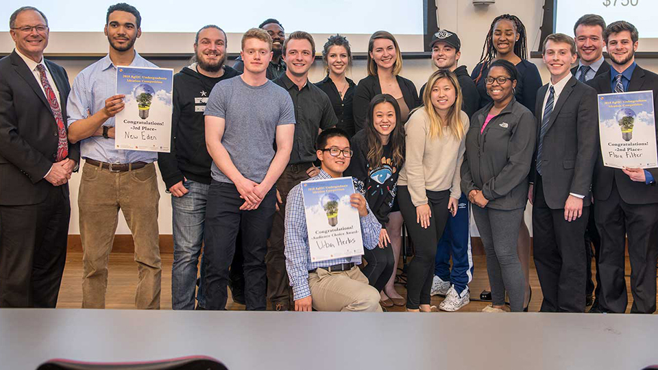 Group of students standing together holding up AgEnterprise posters