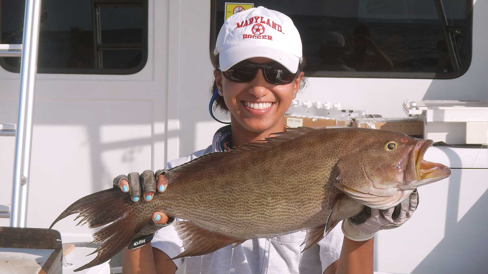 Samara holding up a fish on a boat.