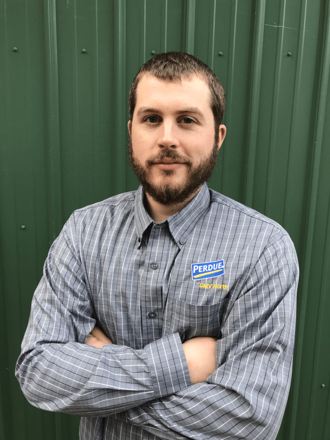 AGNR Alum Bret Bucci stands in front of green background in his company Perdue shirt