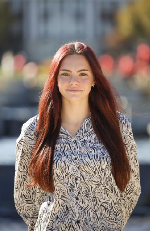 Confident student standing against colorful, blurred background. 