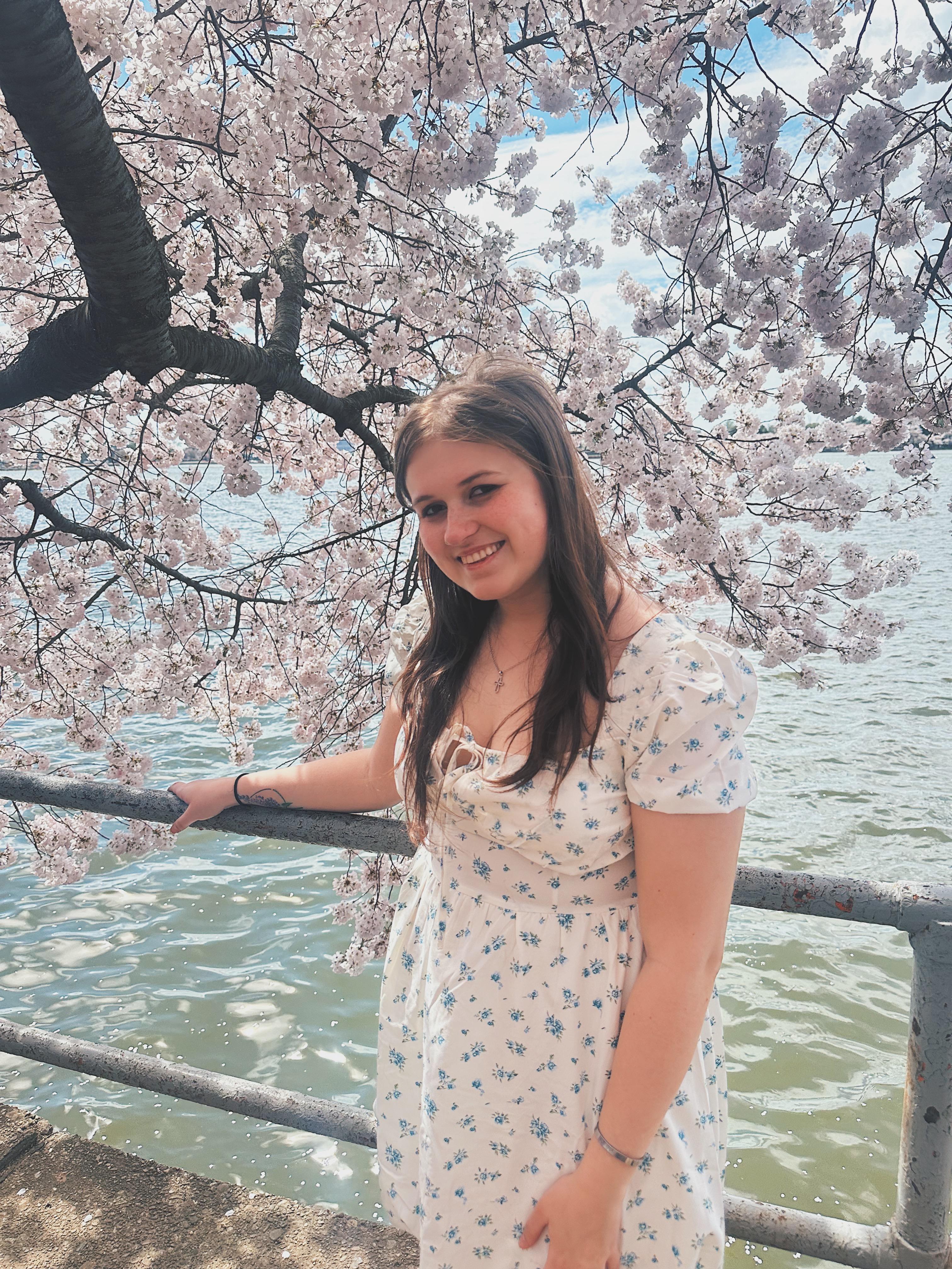 Smiling student posing in front of Washington DC's famous Cherry Blossoms.