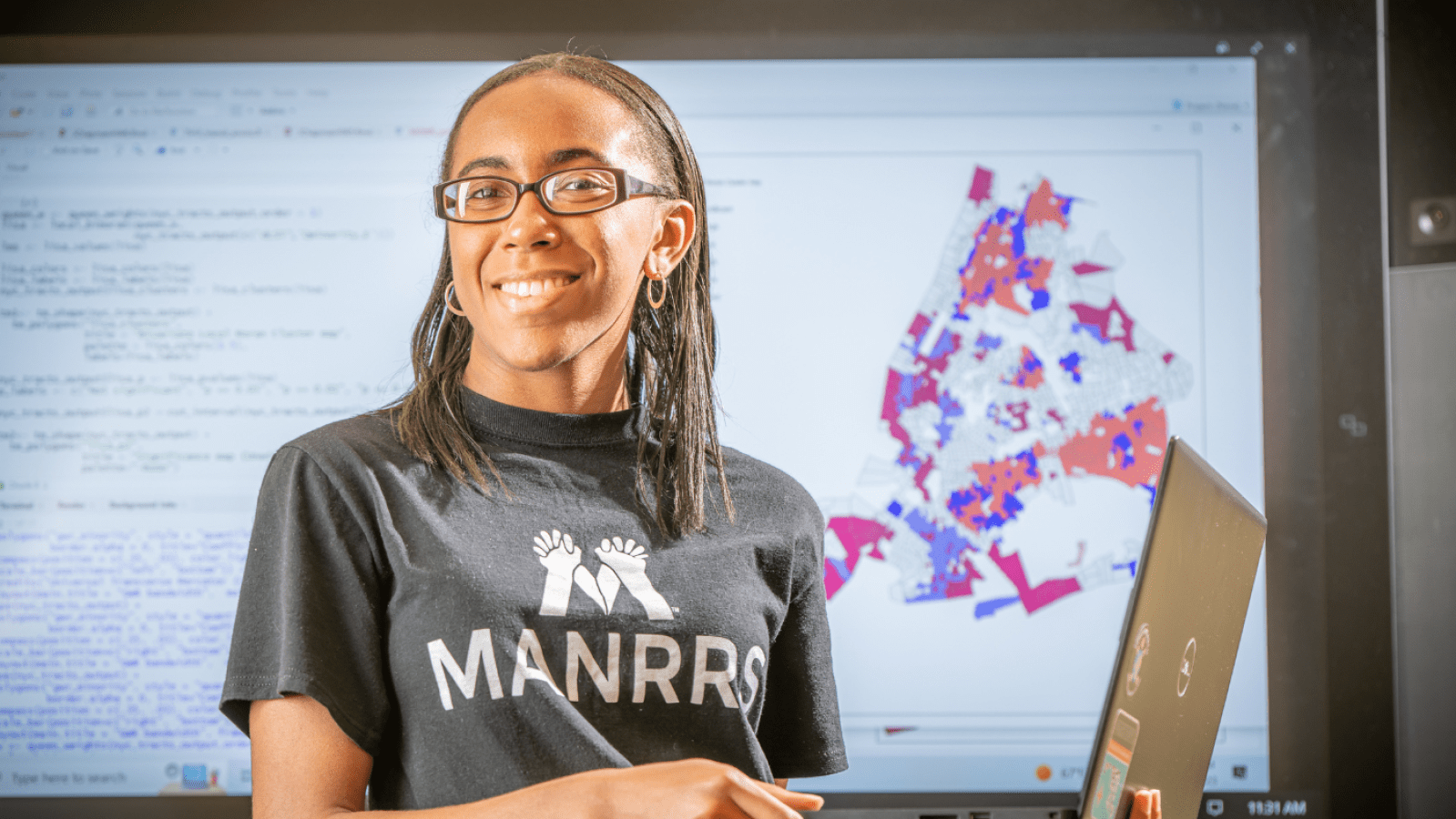 Janna Chapman holding up a laptop in front of a projector screen