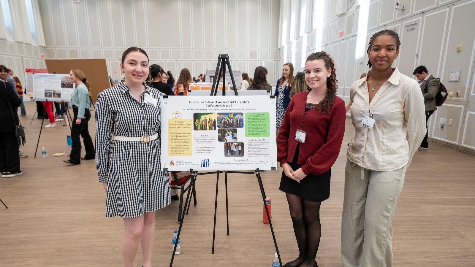 Three students standing in front of their poster presentation at Discovery & Innovation Night at University of Maryland